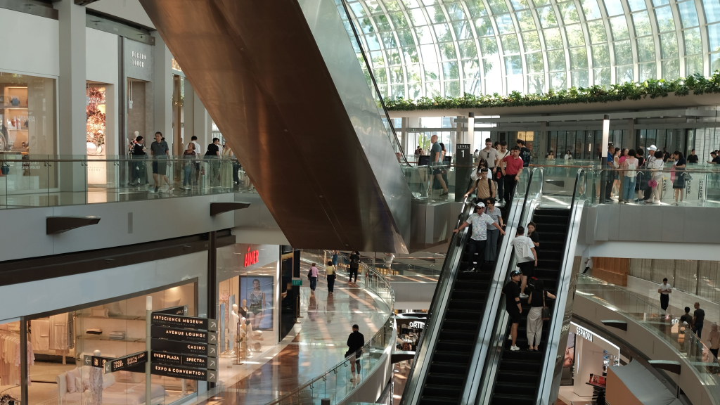 People using escalators inside a busy shopping centre.